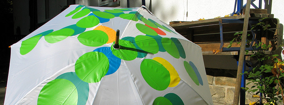 Stillleben im Herbst mit aufgespanntem Regenschirm der Gartenregion Hannover hinter dem kik.-Projekthaus der Künstlerkooperative kik. kunst in kontakt in Hannover Herrenhausen.
