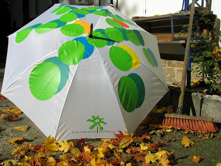 Stillleben im Herbst mit aufgespanntem Regenschirm der Gartenregion Hannover hinter dem kik.-Projekthaus der Künstlerkooperative kik. kunst in kontakt in Hannover Herrenhausen.