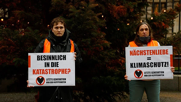 Unterstützer:innen der Letzten Generation vor dem besprühten Weihnachtsbaum in der Mädlerpassage in Leipzig