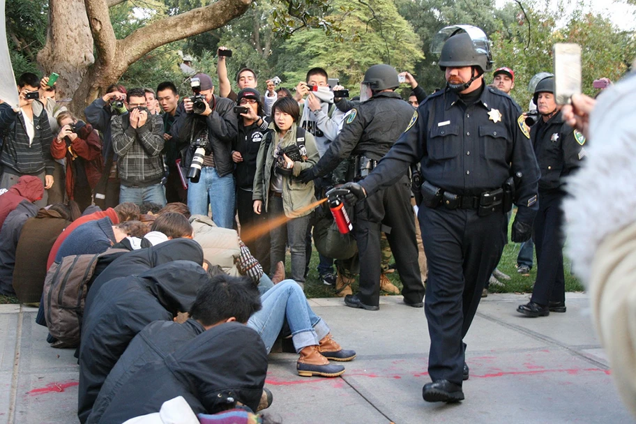 Pfeffersprayeinsatz eines kalifornischen Polizisten im Rahmen einer Sitzblockade der Studierendenprotesten der Occupy-Bewegung im November 2011.