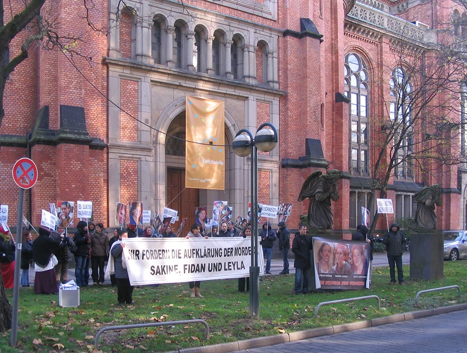 Düsseldorf, vor der Johanneskirche: Demonstrationsgruppe mit Transparent „Wir fordern die Aufklärung der Morde Sakine, Fidan und Leyla“, November 2013.