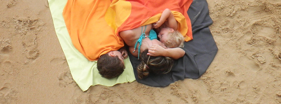 Am Strand von Kontxa in Spanien - Baby an der Brust seiner Mutter.