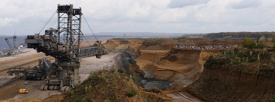 Aktivistinnen und Aktivisten von Ende Gelände stehen an einem Abhang vor einem Bagger im Tagebau Hambach, November 2017.