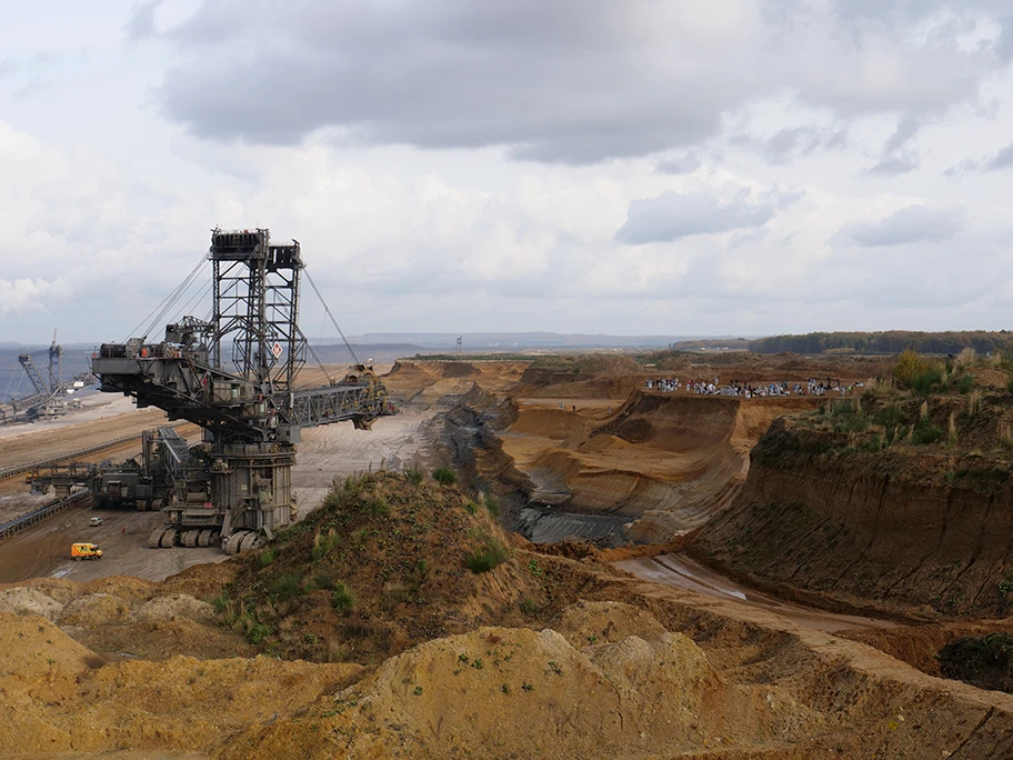 Aktivistinnen und Aktivisten von Ende Gelände stehen an einem Abhang vor einem Bagger im Tagebau Hambach, November 2017.