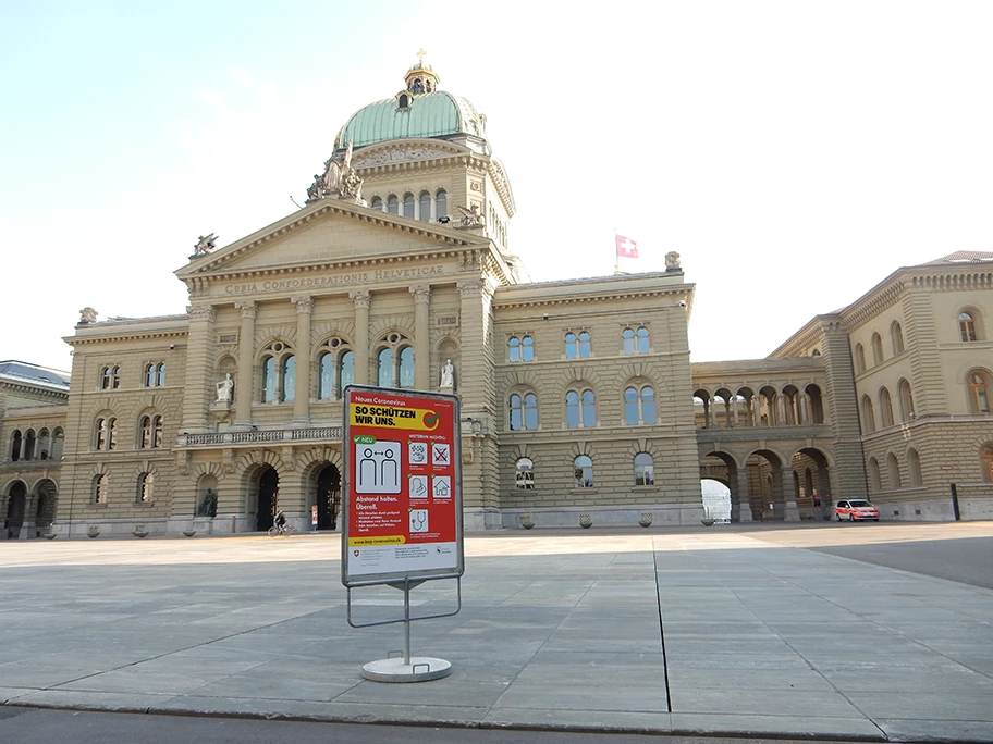 Bundeshaus Bern während COVID-19. Warntafel auf Bundesplatz, Polizeiauto und Sperrgitter Richtung Bundesterrasse.