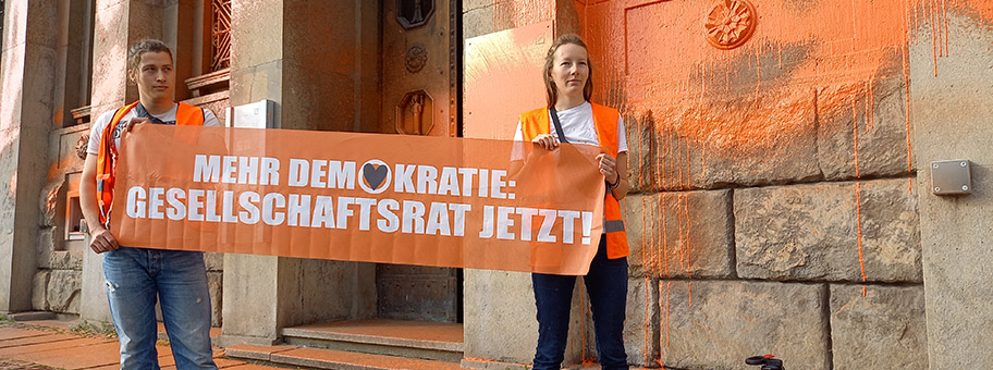 Unterstützer:innen der Letzten Generaton protestieren mit einer Farbaktion gegen die Befeuerung der Kliimakatastrophe durch die Deutsche Bank und für die Einrichtung eines Gesellschaftrats am Falkeplatz in Chemnitz.