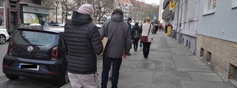 Vor der Postfiliale am Stephansplatz in Hannover warten die Menschen wegen Corona bedingter Zugangsbeschränkungen auf Einlass, Dezember 2020.