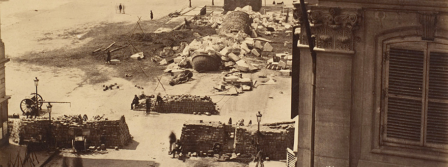 Die Reste der Vendôme-Säule, die als Symbol der Herrschaft Napoléons von den Kommunarden 1871 umgestürzt worden war; im Vordergrund Barrikaden.
