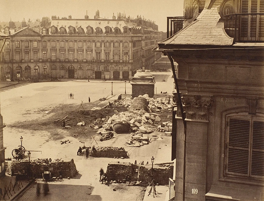 Die Reste der Vendôme-Säule, die als Symbol der Herrschaft Napoléons von den Kommunarden 1871 umgestürzt worden war; im Vordergrund Barrikaden. Die Pariser Kommune von 1871 gilt als historisches Vorbild des Rätekommunismus.