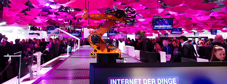 Der Messestand der Deutschen Telekom auf der CeBit 2015. Er zeigt sich bewegende Roboterarme, die magentafarbene Regenschirme halten. Das soll auf das Internet der Dinge verweisen.