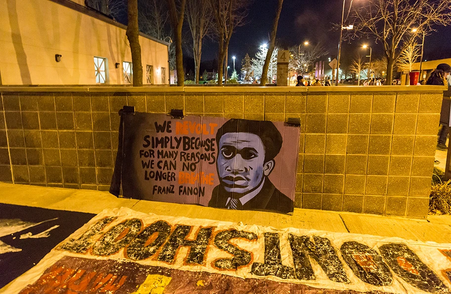 Protestschild mit Frantz Fanon-Zitat vor dem Polizeigebäude in Minneapolis, November 2015.