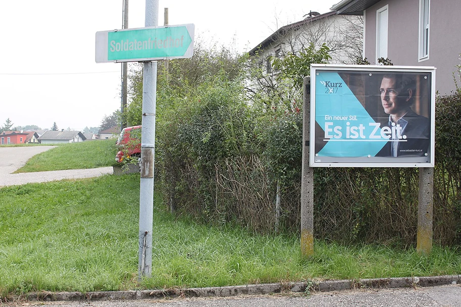 Wahlplakat der ÖVP «Es ist Zeit» mit Situierung neben dem Hinweisschild «Soldatenfriedhof».