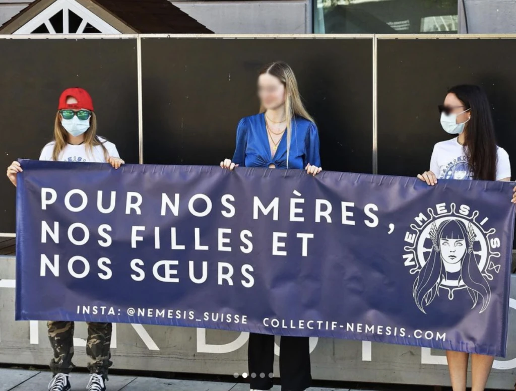 Drei Frauen von Némesis Suisse mit einem Transparent am Rande der feministischen Demo am 14. Juni 2022 in Lausanne.