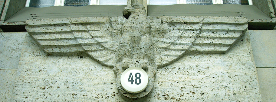 NS-Reichsadler über dem Hauptportal des Finanzamts Charlottenburg (Berlin); das Hakenkreuz an der Stelle der Hausnummer (Bismarckstrasse 48) wurde nach 1945 entfernt.