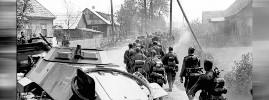 Deutsche Soldaten marschieren neben einem Panzerspähwagen durch eine Ortschaft im Norden von Russland, Juni 1941.