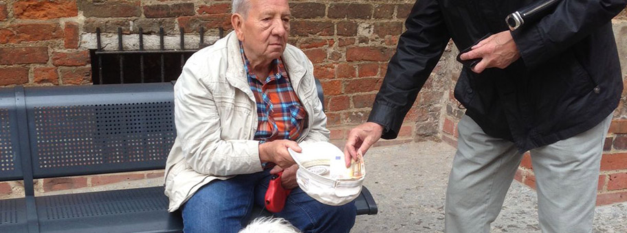 Rentner erbettelt Geld für Essen für sich und seinen Hund vor der Kirche in Wismar von einem begüterten Touristen aus Nordrhein-Westfalen.