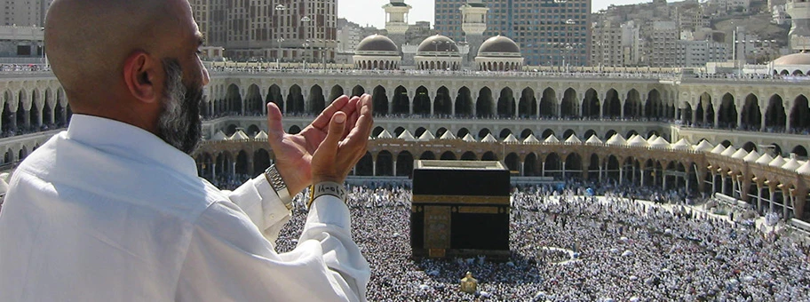 Pilger beim Bittgebet in Mekka, im Mittelgrund die Kaaba.