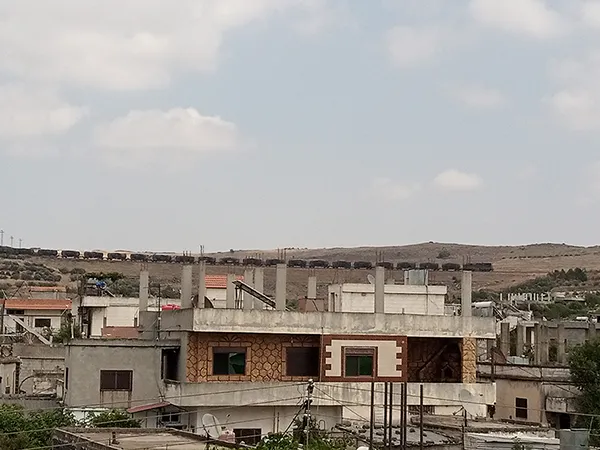Ein Güterzug der Syrischen Eisenbahn (CFS) östlich des Dorfes Umm Haratayn al-Gharbiyah im westlichen Umland von Homs (Bezirk Talkalakh), Juli 2026.