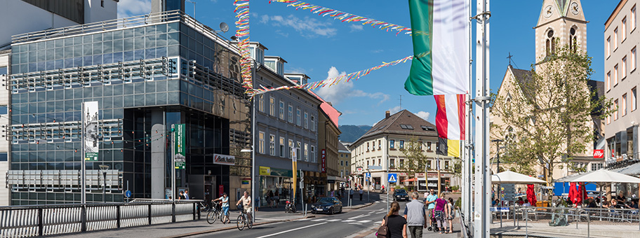 Bahnhofstrasse mit dem Gebäude der Bank Austria Creditanstalt und der Nikolaiplatz mit der Nikolaikirche, Stataturstadt Villach, Kärnten, Österreich.