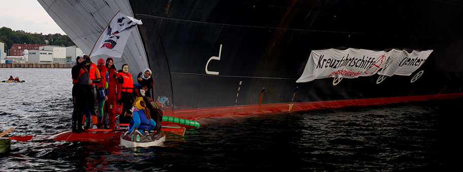 Blockade des Kreuzfahrtschiffes Zuiderdam als Protest gegen die steigenden klimaschädlichen Emissionen der Kreuzfahrtbranche, die häufig schlechten Arbeitsbedingungen an Bord und negativen ökologischen, sozialen und ökonomischen Auswirkungen auf die Zielorte des Kreuzfahrttourismus. Eine Gruppe von AktivistInnen kreuzt mit kleinen Booten vor dem Bug der Zuiderdam und ist auf den Wulstbug geklettert und verhindert so das Ablegen des Schiffes aus dem Kieler Hafen. An der Schiffswand ist ein Banner mit der Aufschrift