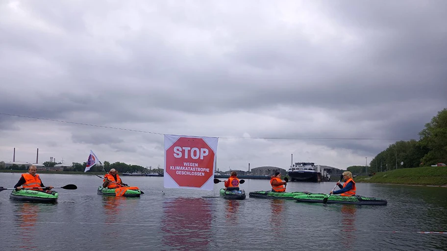 Klimaaktivst:innen der Letzten Generation blockieren mit Kajaks die Kanalzufahrt zum Ölhafen Karlsruhe.